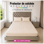 Referencia visual de un protector acolchado color beige con dos fundas de almohada; el diseño del acolchado puede variar